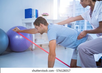 Female physiotherapist assisting a male patient while exercising in the clinic - Powered by Shutterstock