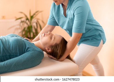 Female physiotherapist or a chiropractor adjusting patients neck. Physiotherapy, rehabilitation concept. Side view cropped shot. - Powered by Shutterstock