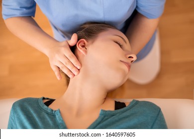 Female physiotherapist or a chiropractor adjusting patients neck. Physiotherapy, rehabilitation concept. Top view close up.