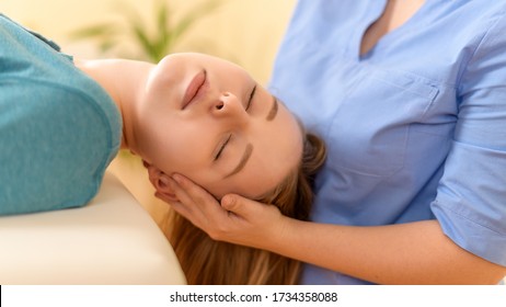 Female physiotherapist or a chiropractor adjusting patients neck. Physiotherapy, rehabilitation concept. Side view cropped shot. - Powered by Shutterstock