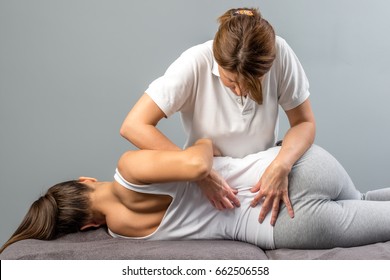 Female physiotherapist doing manipulative spine treatment on young patient.