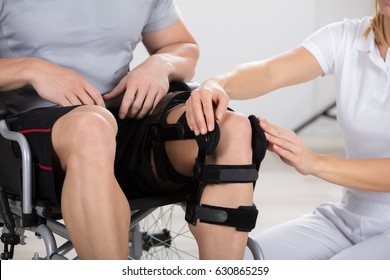 Female Physiotherapist Fixing Knee Braces On Man's Leg In A Clinic - Powered by Shutterstock