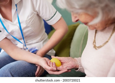 Female Physiotherapist Getting Senior Woman To Squeeze Rubber Ball At Home - Shutterstock ID 2003720021
