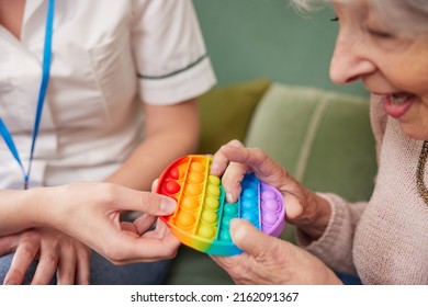 Female Physiotherapist Getting Senior Woman To Squeeze Rubber Ball At Home - Powered by Shutterstock