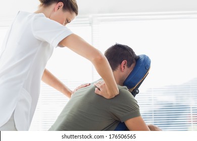 Female physiotherapist giving back massage to man in hospital