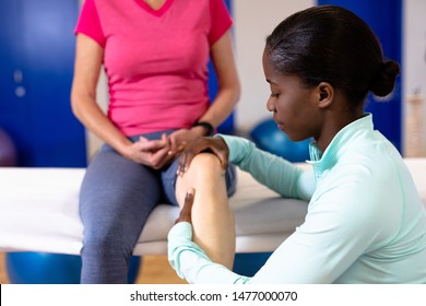 Female physiotherapist giving leg massage to active senior woman in sports center. Sports Rehab Centre with physiotherapists and patients working together towards healing
