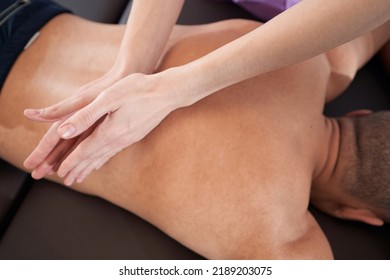 Female Physiotherapist Hands Massaging Man Back In Clinic