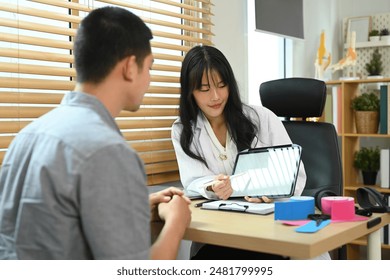 Female physiotherapist showing digital tablet giving consultation to male patient at rehab clinic - Powered by Shutterstock