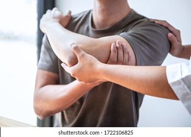 Female Physiotherapist working examining treating injured arm of athlete male patient, stretching and exercise, Doing the Rehabilitation therapy pain in clinic.