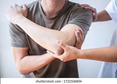 Female Physiotherapist working examining treating injured arm of athlete male patient, stretching and exercise, Doing the Rehabilitation therapy pain in clinic.