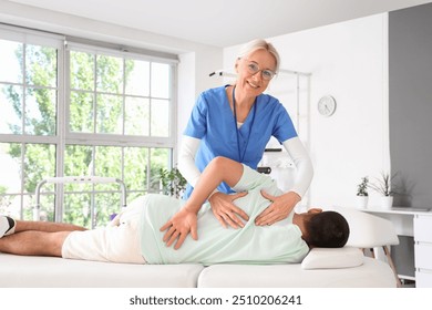 Female physiotherapist working with young man on couch in rehabilitation center - Powered by Shutterstock