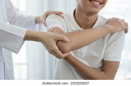 Female physiotherapists provide assistance to male patients with elbow injuries examine patients in rehabilitation centers. Rehabilitation physiotherapy concept. - Shutterstock ID 1923292037