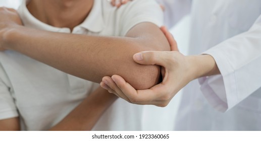 Female physiotherapists provide assistance to male patients with elbow injuries examine patients in rehabilitation centers. Rehabilitation physiotherapy concept. - Powered by Shutterstock