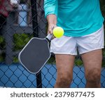 Female pickleball player stikes the ball with a volley.