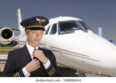 Female pilot smiling in front of airplane