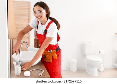 Female Plumber Fixing Sink In Bathroom