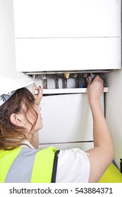 Female Plumber Servicing Central Heating Boiler