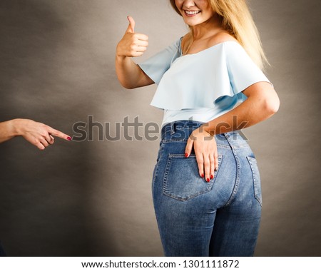 Female plus size hips buttocks wearing blue jeans, woman presenting fashionable outfit. Fashion clothing femininity concept. Gray background