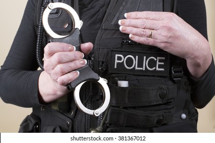 Female Police Office Holding A Pair Of Rigid Handcuffs