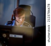 Female police officer in a call center, listening carefully to an emergency call from a person in distress