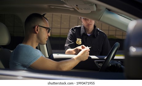 Female Police Officer Checking Documents Of Male Driver