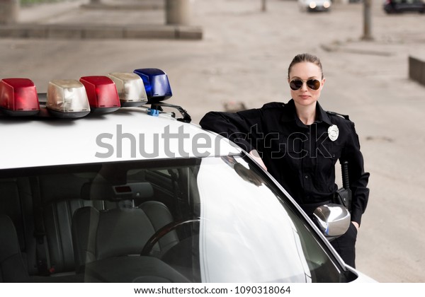female police
officer leaning on patrol
car