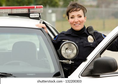 A Female Police Officer Smiling Next To Her Police Car.