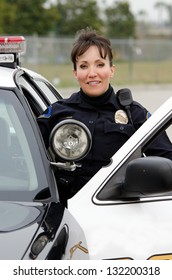 A Female Police Officer Smiling Next To Her Police Car.