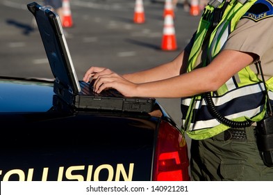 A Female Police Officer Types On Her Lap Top Computer While On A Call.