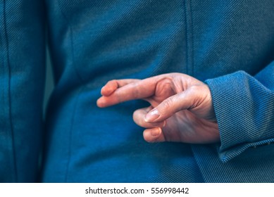 Female Politician In Elegant Blue Suit Has Crossed Fingers Behind Her Back As A Form Of Hand Gesture When People Are Telling Lies