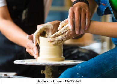 Female Potter creating a bowl on a Potters wheel, the master potter helping her - Powered by Shutterstock