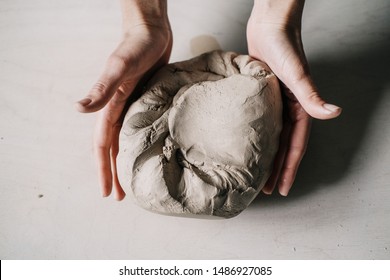 Female potter hands working with clay in workshop. White desk on background - Powered by Shutterstock