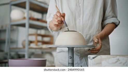 Female Potter Painting a White Clay Bowl in Pottery Studio - Powered by Shutterstock