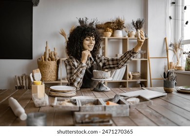 Female potter recording a vlog while working on a clay sculpture in a cozy and well-lit pottery studio. - Powered by Shutterstock