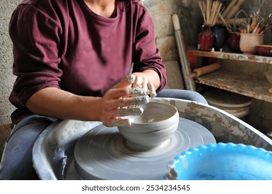 Female potter shaping clay on wheel in home studio. - Powered by Shutterstock