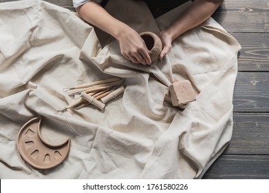 Female potter shaping piece of clay at the table. Woman making ceramic item. Pottery working, handmade and creative skills at arts studio. - Powered by Shutterstock
