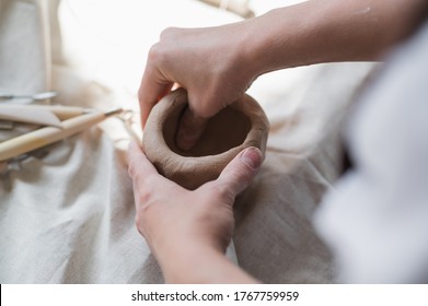 Female potter shaping piece of clay at the table. Woman making ceramic item. Pottery working, handmade and creative skills at arts studio. - Powered by Shutterstock