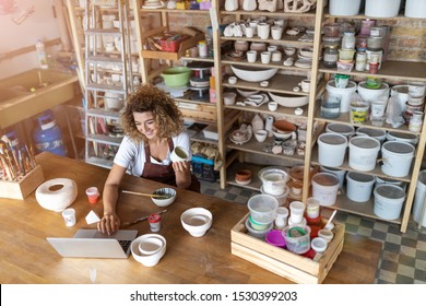 Female Potter Using Laptop In Art Studio 