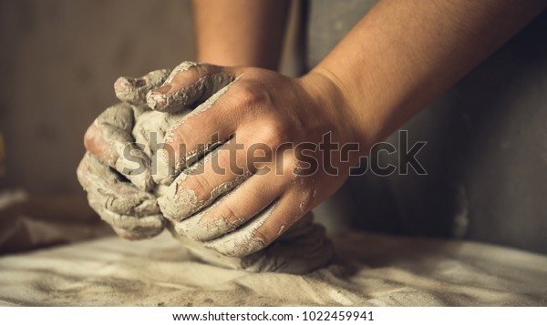 Female potter works\
with clay, craftsman hands close up, kneads and moistens the clay\
before work, toned