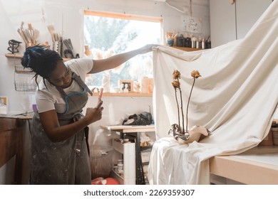 Female pottery artist business owner taking photos of her ceramics - Powered by Shutterstock