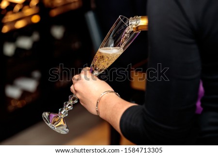 A female pouring champagne in a champagne glass with a blurred background