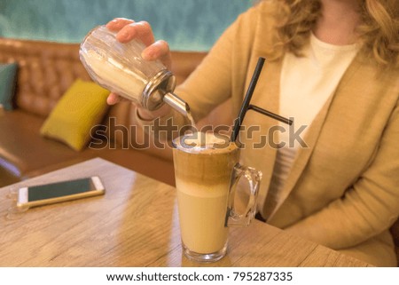 Female pouring sugar into a cup of coffee in cafe