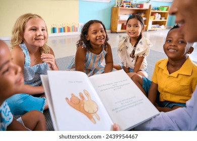 Female Primary Or Elementary School Teacher Reads Story To Multi-Cultural Class Seated In Classroom - Powered by Shutterstock