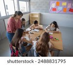 Female primary school teacher explaining in class to a group of students sitting at desks. Back to school