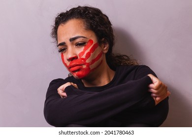 Female with a print on her mouth, demonstrating violence on women. Woman protesting against domestic violence and abuse in the background.
