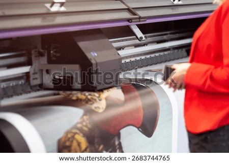 Female printing operator and large format printing machine. Industry