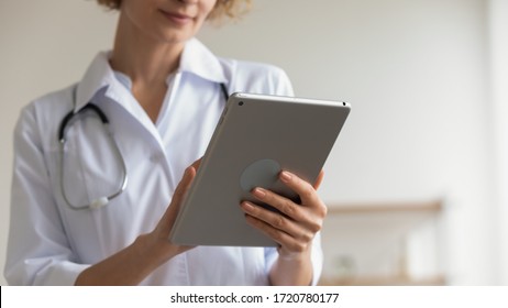 Female professional medic doctor holding modern pad using digital tablet remote telemedicine app in hospital working online. Healthcare technology telehealth ehealth concept. Close up view, copy space - Powered by Shutterstock