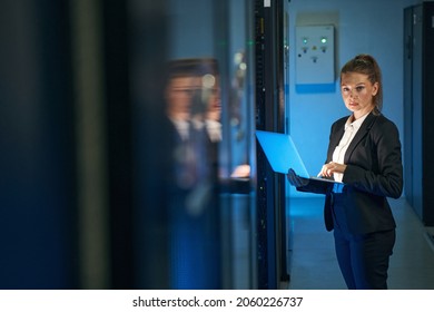 Female IT professional working in server room with laptop