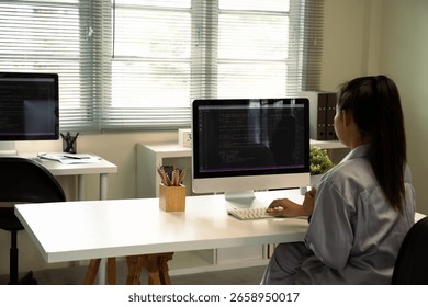 Female programmer coding on desktop computer in modern office