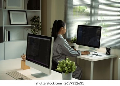 Female programmer coding on a desktop computer in a bright, modern office